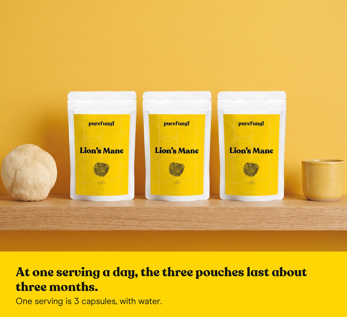 Three Lion's Mane capsules pouches on a wooden shelf with a Lion's Mane mushroom and a yellow cup